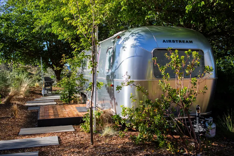 Airstream 4A among green trees on a sunny day