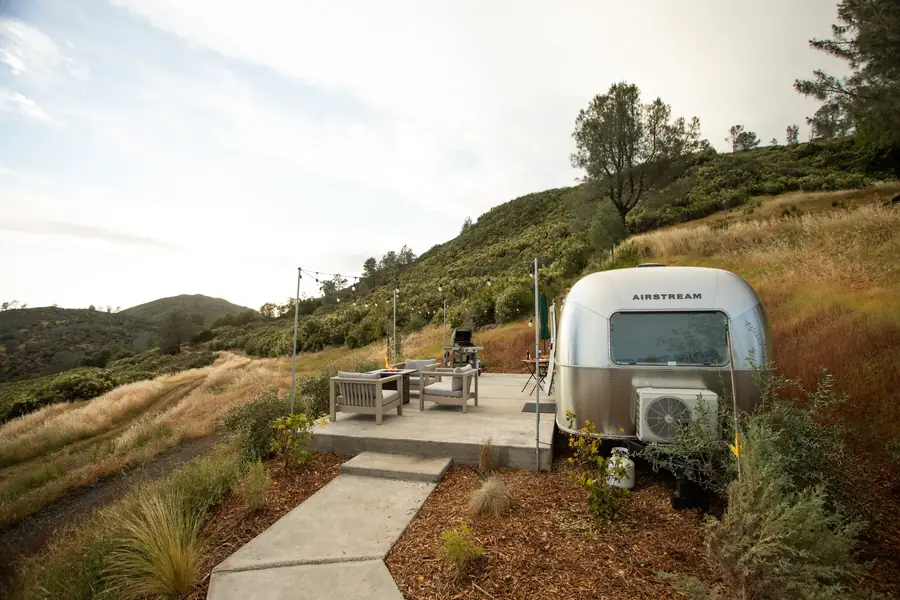 Airstream 5A and its furnished patio on the hillside at golden hour