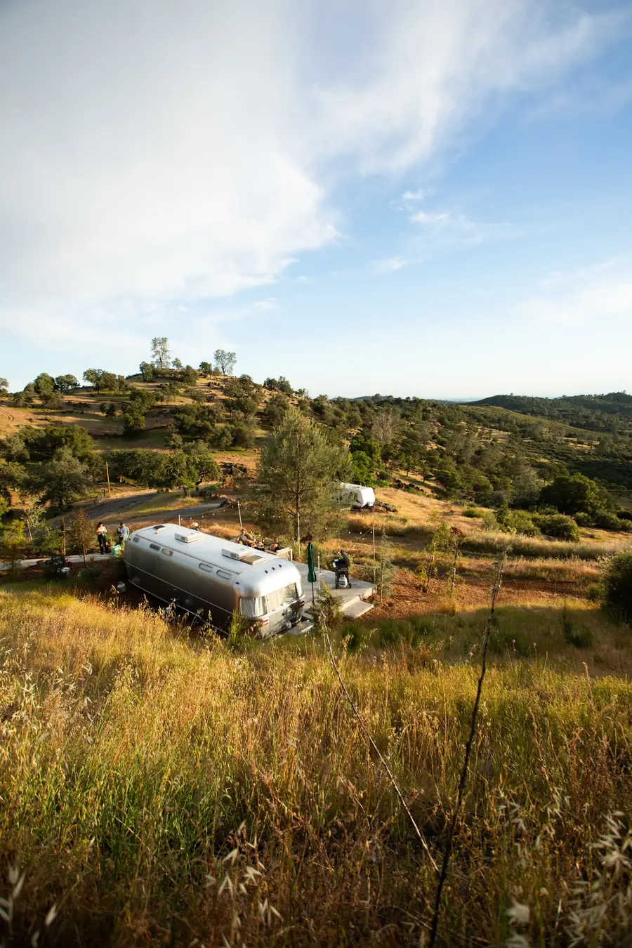 Airstream 5A in golden grass on the hillside, with the foothills beyond