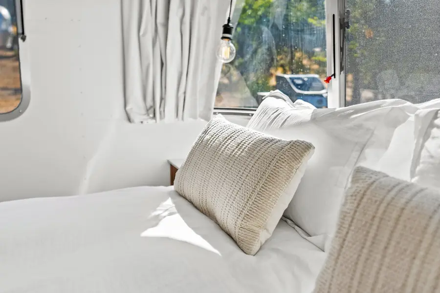 Close view of soft pillows on the queen bed beside a window with trees outside