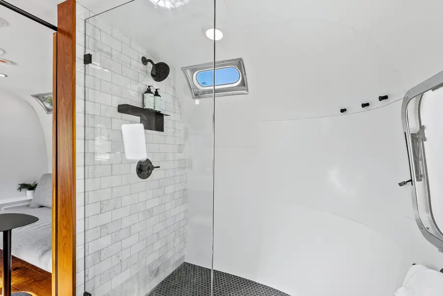 Glass walk-in shower with white subway tile and black fixtures