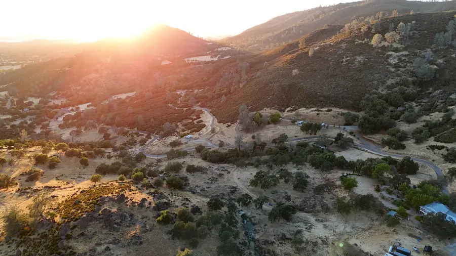 Golden-hour sun setting over oak-covered foothill ridges above Mariposa Highlands