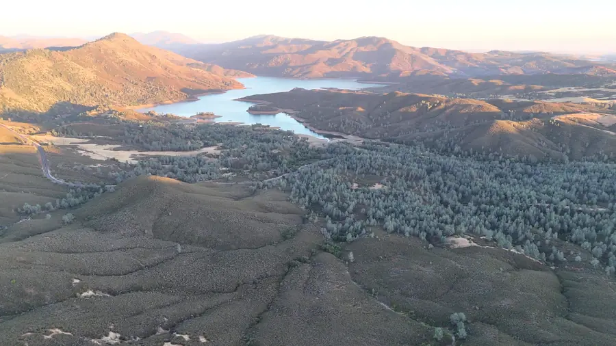 Aerial view at golden hour of Lake McClure winding between foothill ridges near Mariposa Highlands