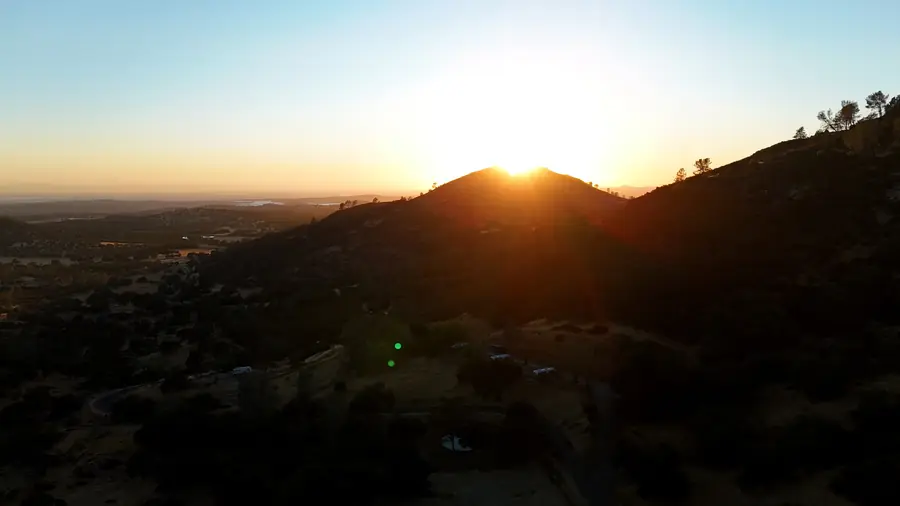 Drone view of the sun setting over the foothill ridges around Penon Blanco Peak