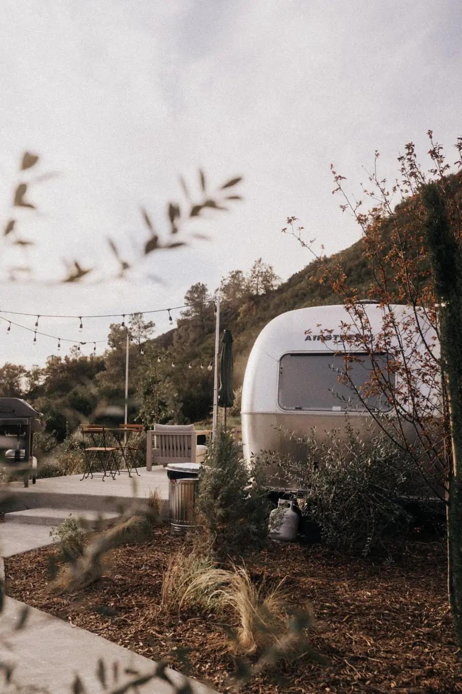 An Airstream and its patio under string lights in the evening