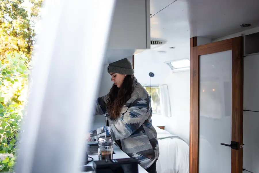 A guest making coffee at the window of an Airstream kitchenette