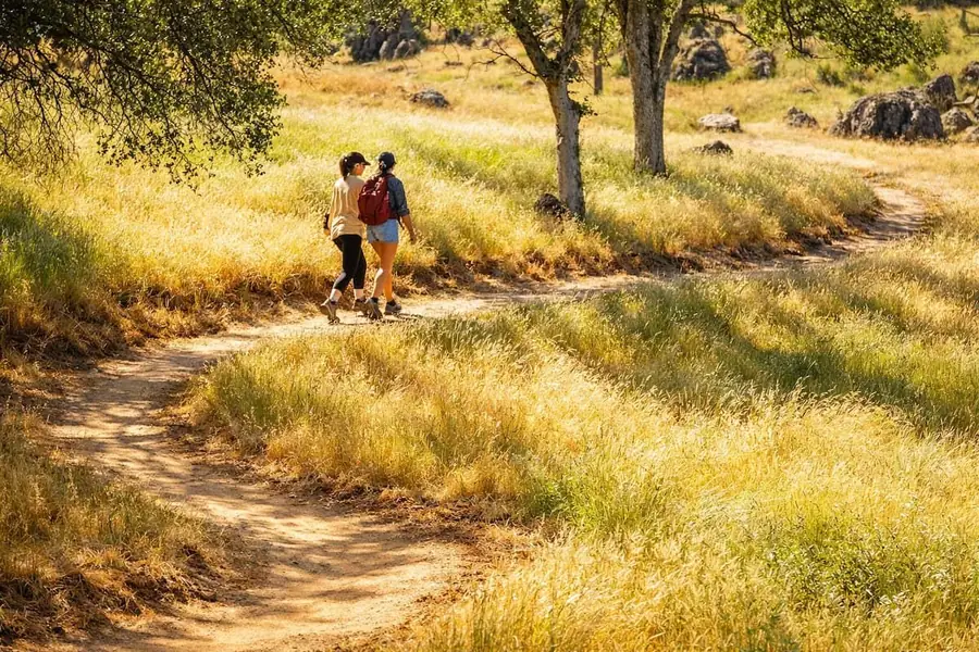 Two people walking a private trail through golden grass and oaks