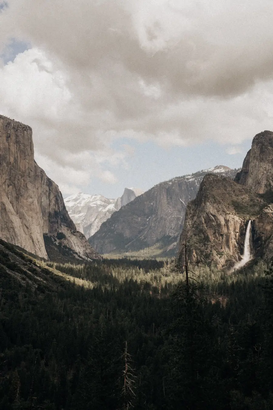 Tunnel View in Yosemite: El Capitan, Bridalveil Fall and Half Dome under clouds above the forested valley