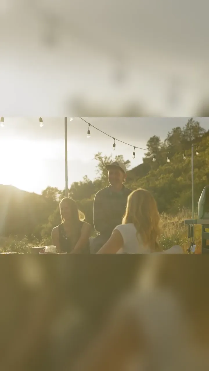 Guests toasting under string lights at sunset, then sitting by a propane fire table after dark